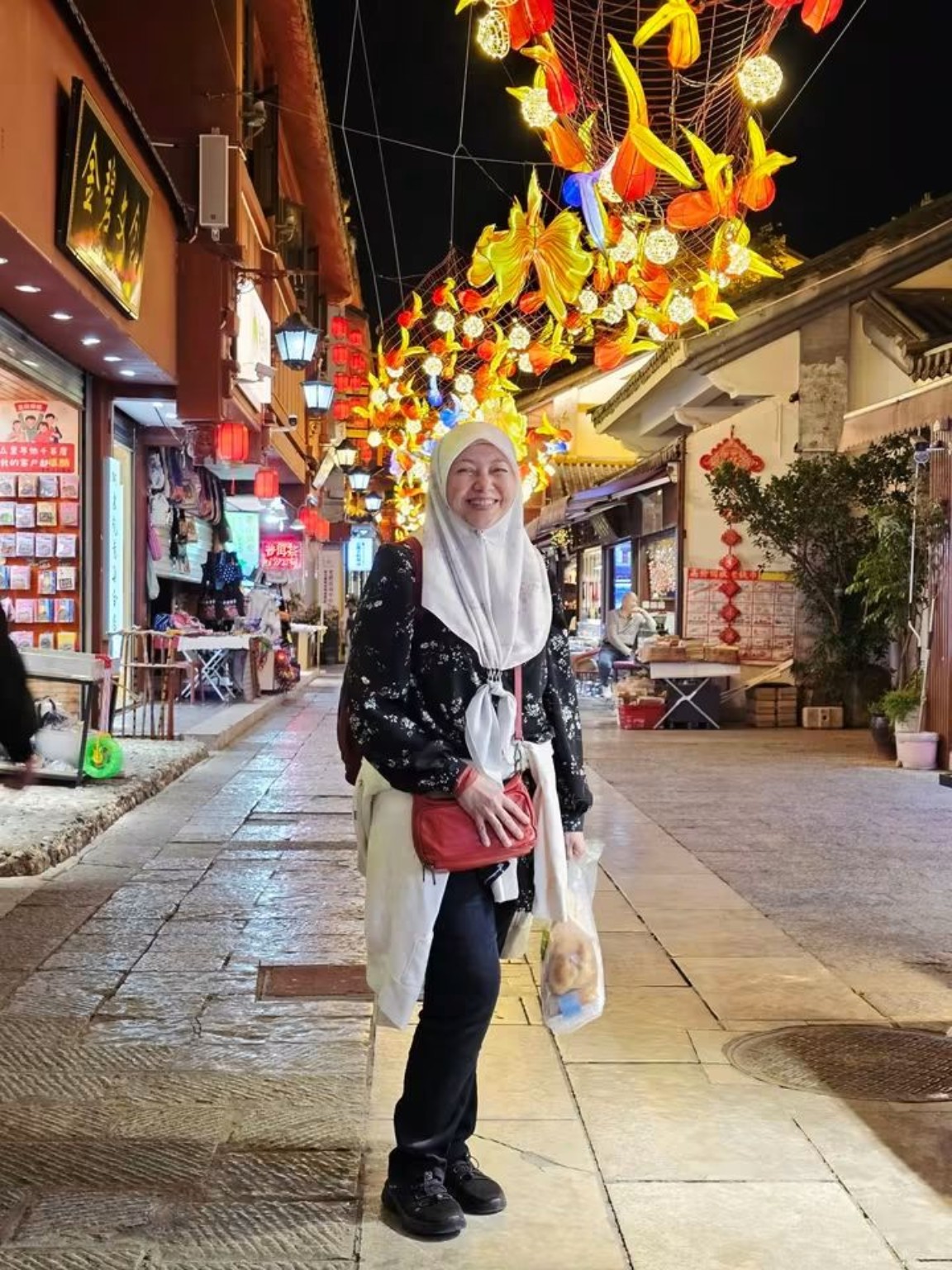 Kak Sukma tersenyum di jalan yang dihiasi tanglung.